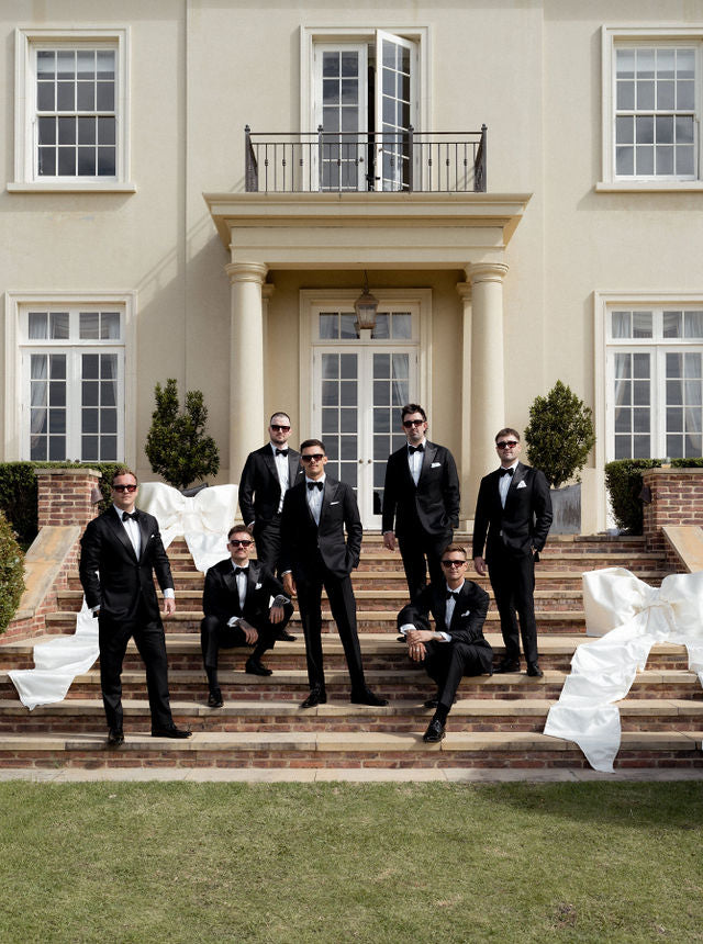 Em and Joel’s wedding party posing on the steps in black suits and sunglasses